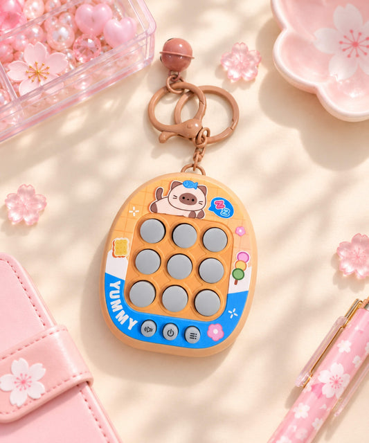 Orange Yummy 3-in-1 Tic Tac Toe game keychain in a soft pink lifestyle setting