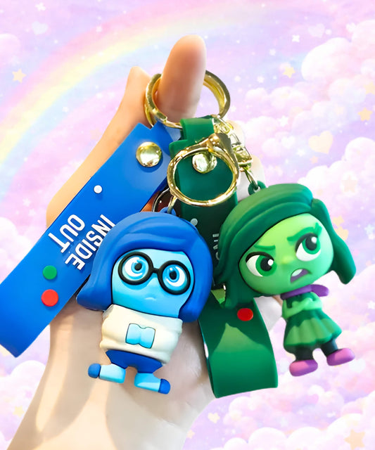 Cute emotion character keychains in blue and green colours held in hand, cartoon mood bag charms with pastel rainbow background