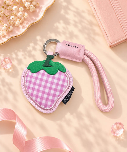 Pink gingham strawberry PU leather bag charm keychain styled on a soft pink background