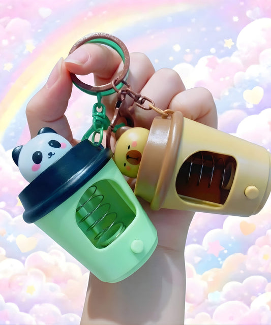 Pop up coffee cup LED keychain with spring animal design held in hand, light up interactive bag charm with pastel rainbow background