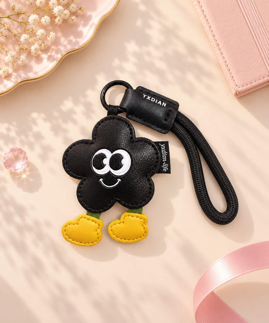 Black Flower PU leather bag charm keychain styled on a soft pink neutral background