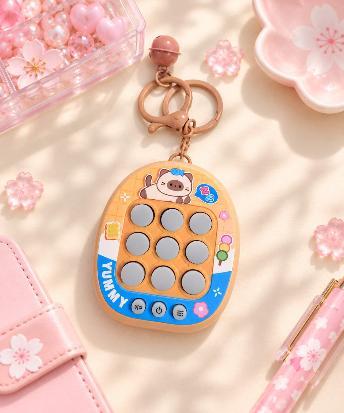 Orange Yummy 3-in-1 Tic Tac Toe game keychain in a soft pink lifestyle setting