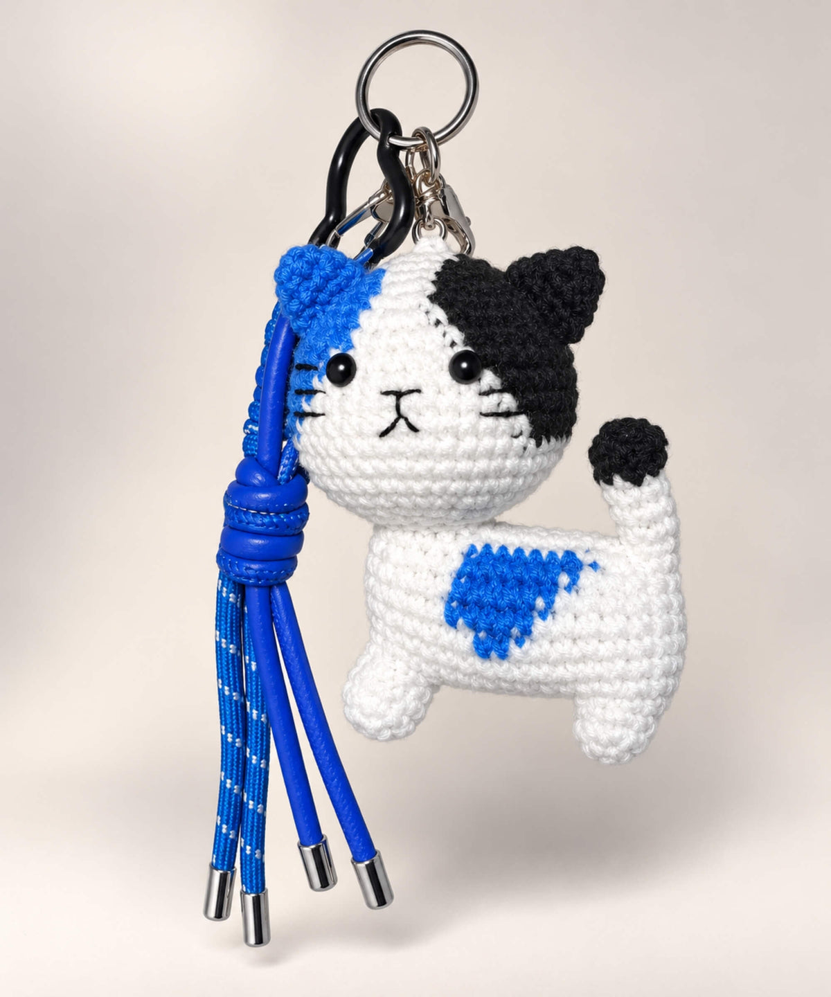 Blue patch cat crochet keychain with black and white details and blue hanging cords
