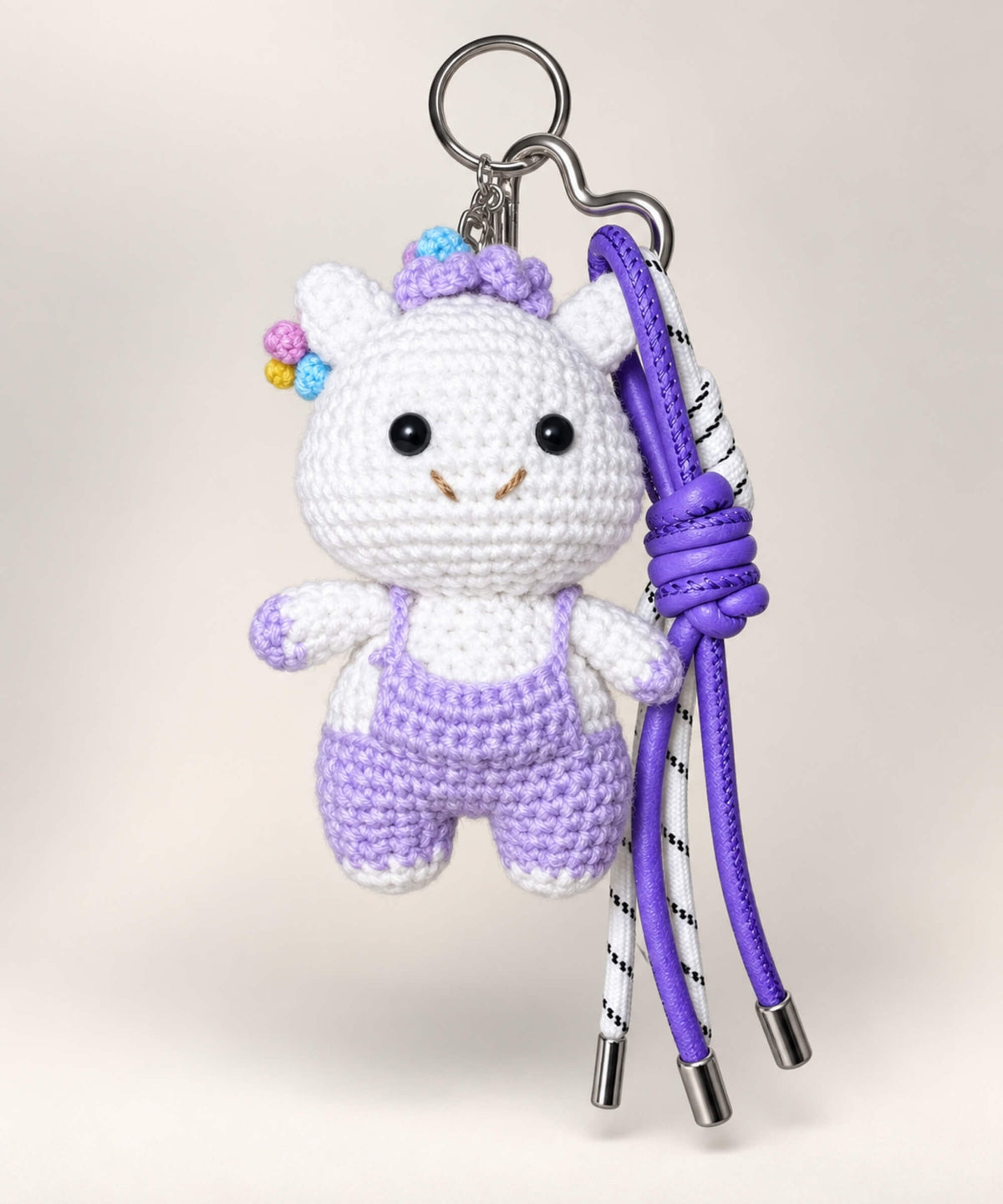 Braided cow crochet keychain wearing purple overalls with colourful details