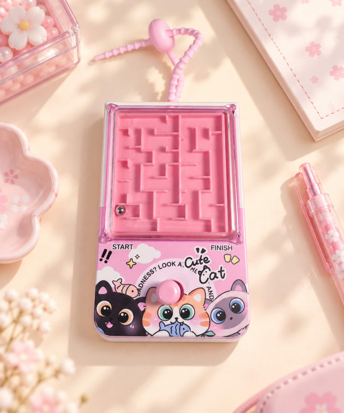 Pink Cat Ball Maze Game Keychain styled on a desk