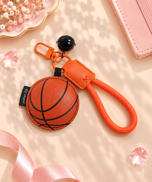Basketball PU leather-look bag charm keychain styled on a warm neutral background