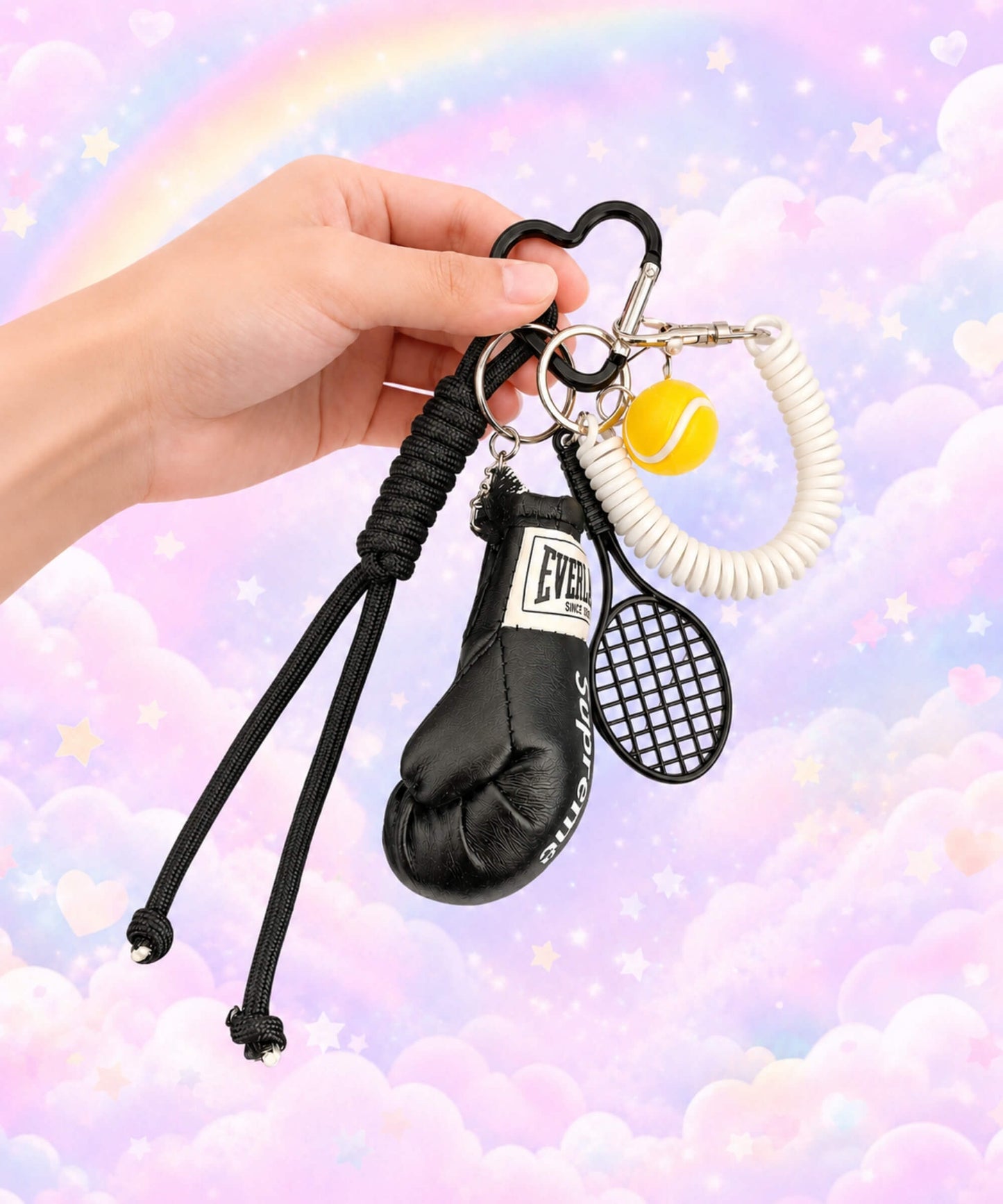 Black boxing glove and tennis rope keychain held by hand with pastel rainbow background