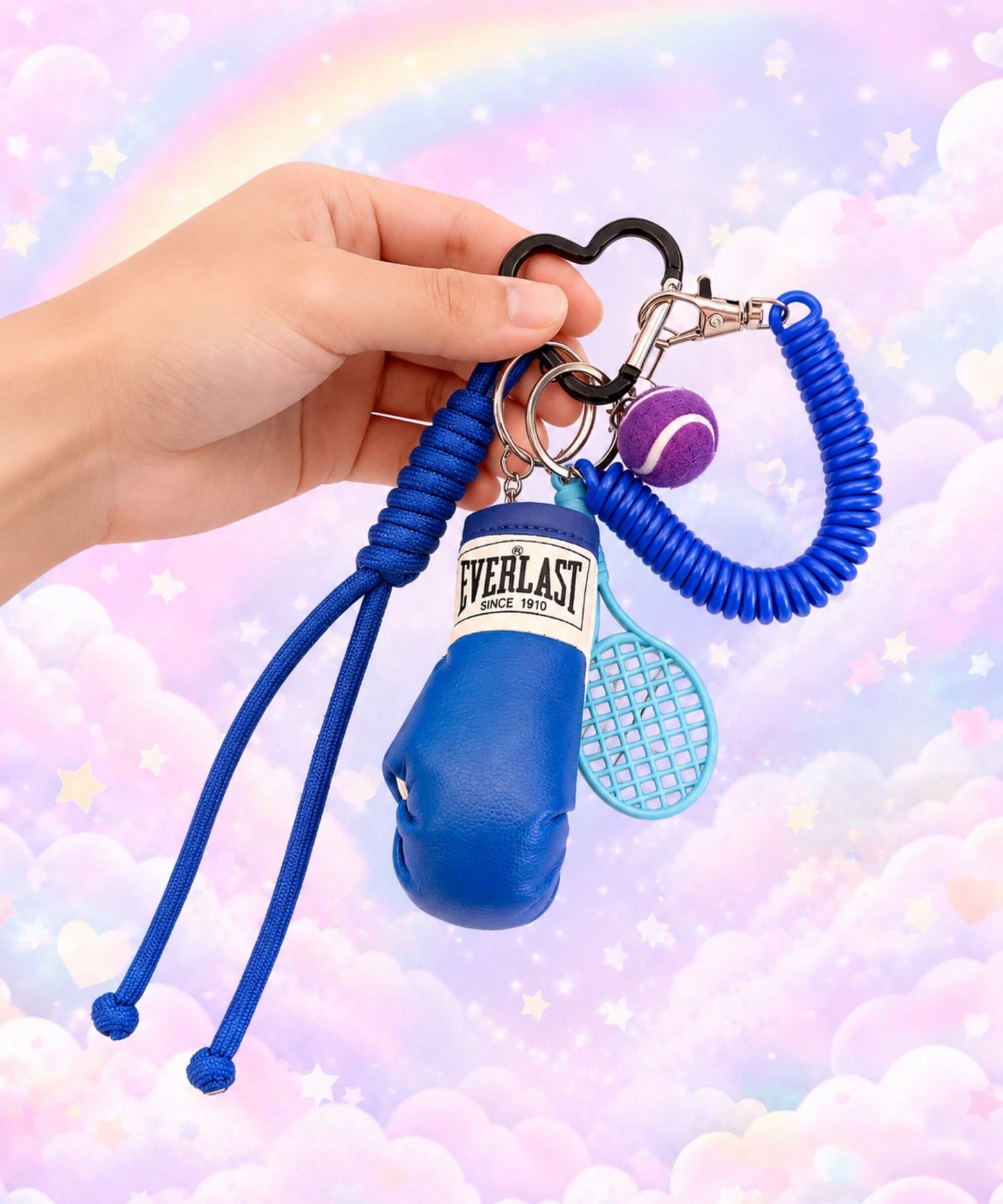 Blue boxing glove and tennis rope keychain held by hand with pastel rainbow background