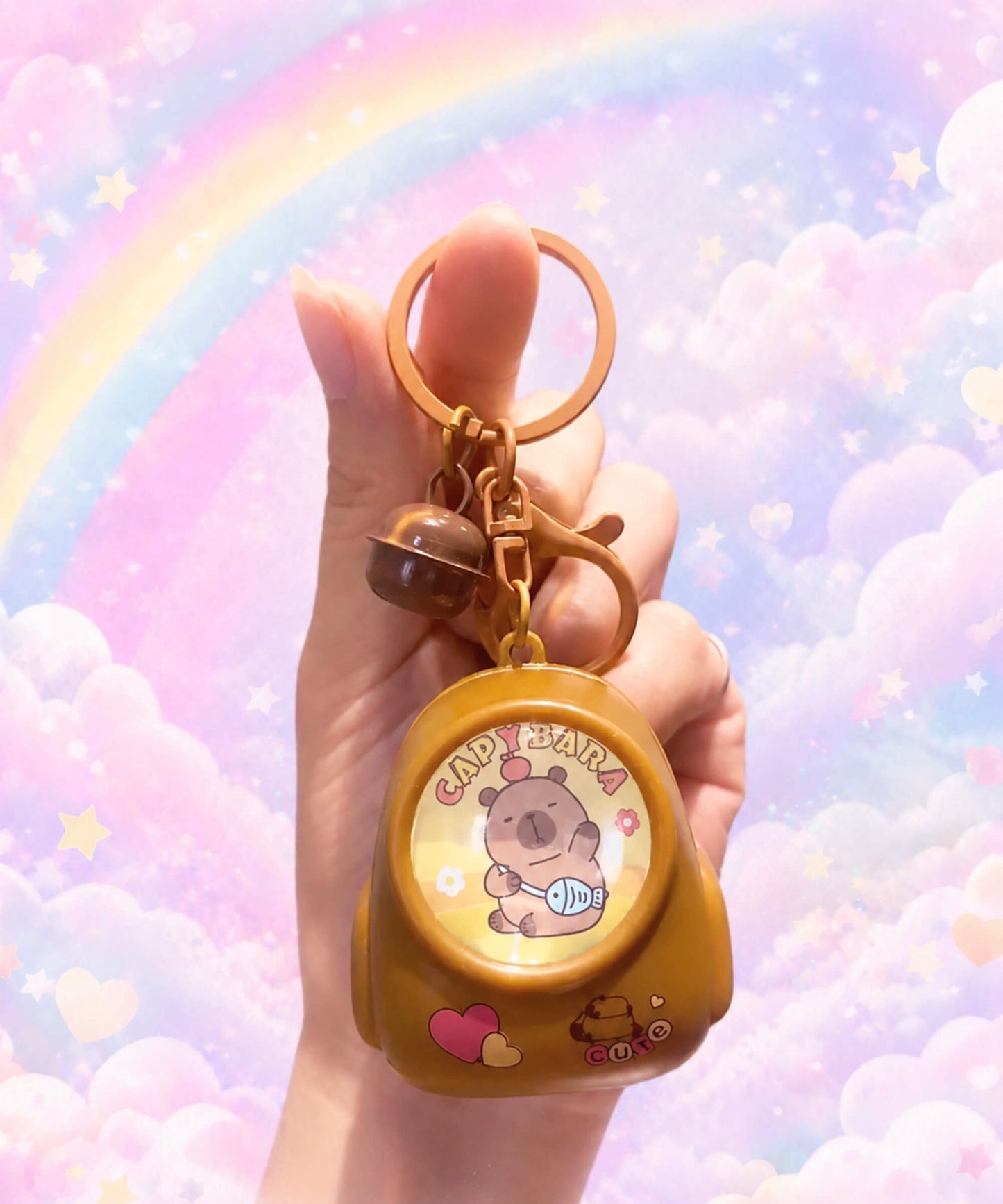 Hand holding capybara fish light-up keychain with pastel rainbow background