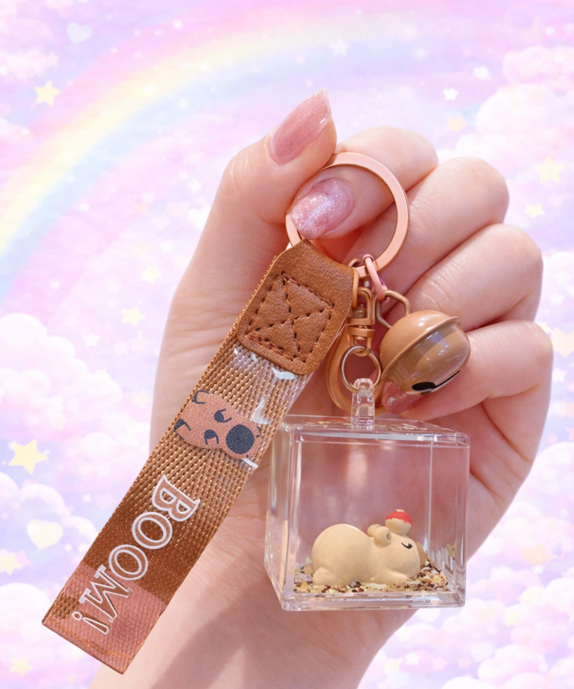 Cute capybara liquid shaker keychain in acrylic cube held in hand, floating glitter bag charm with pastel rainbow background