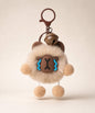 Capybara plush keychain with fluffy body, brown charm details and dangling pom pom feet