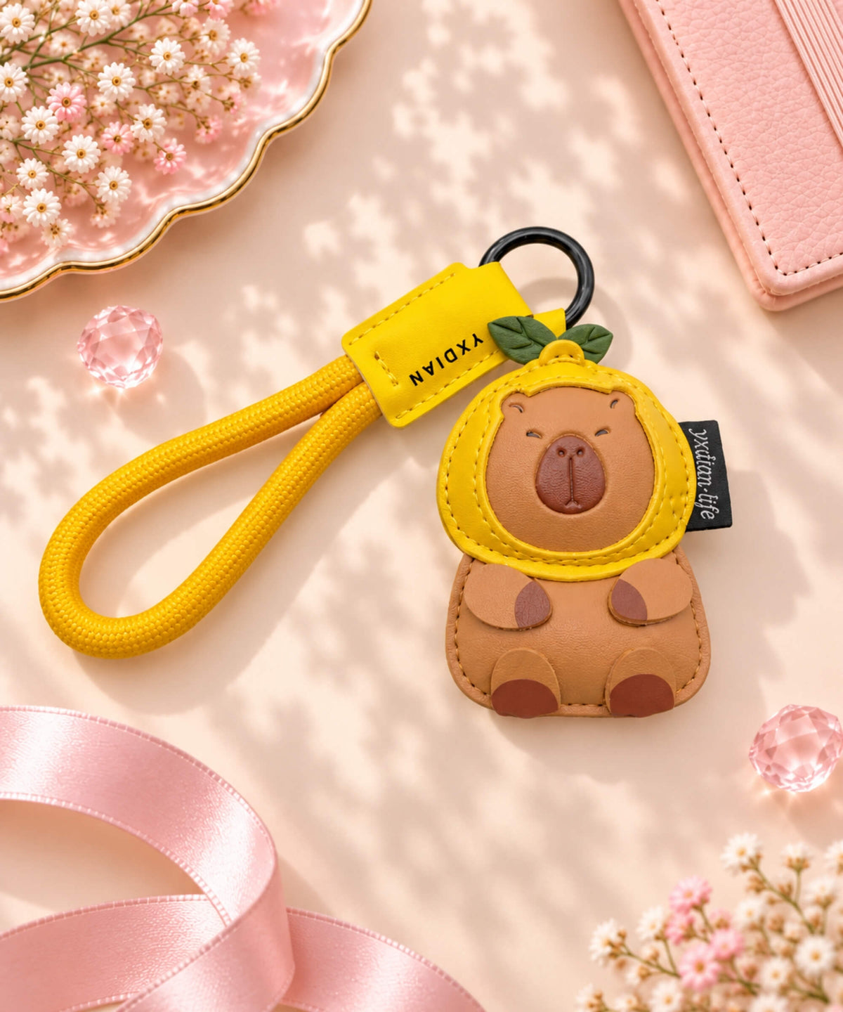 Orange Capybara PU leather bag charm keychain styled on a soft pink neutral background