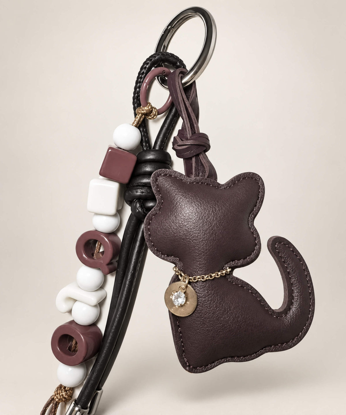 Close-up of Dark Brown cat PU leather bag charm keychain with bead and cord details