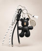 Black bear PU leather bag charm keychain with a badminton racket charm and shuttlecock charm on a neutral background.