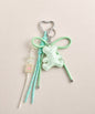Green bear PU leather bag charm keychain with a sparkle charm, star charm and card charm on a neutral background.