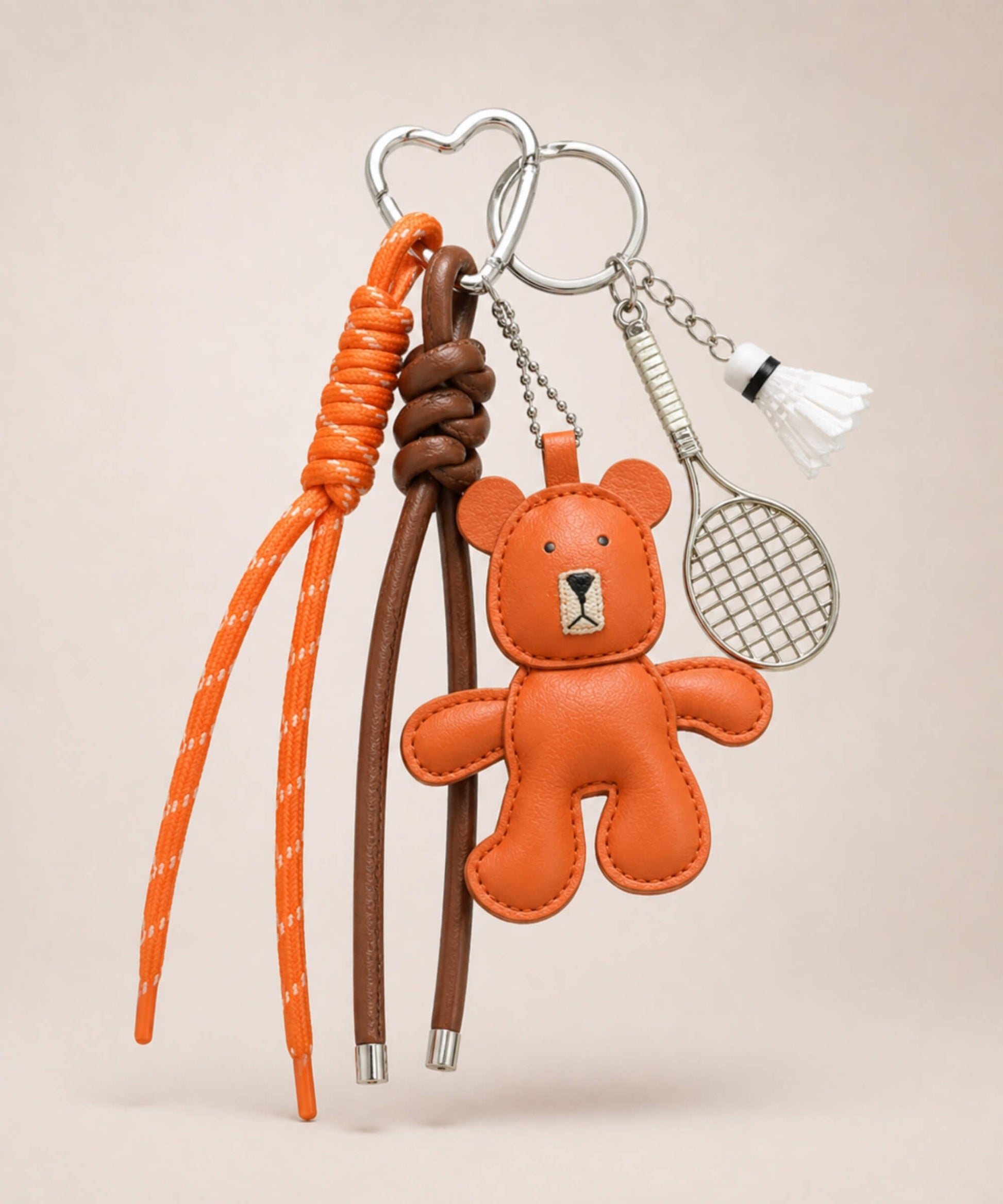 Orange bear PU leather bag charm keychain with a badminton racket charm and shuttlecock charm on a neutral background.