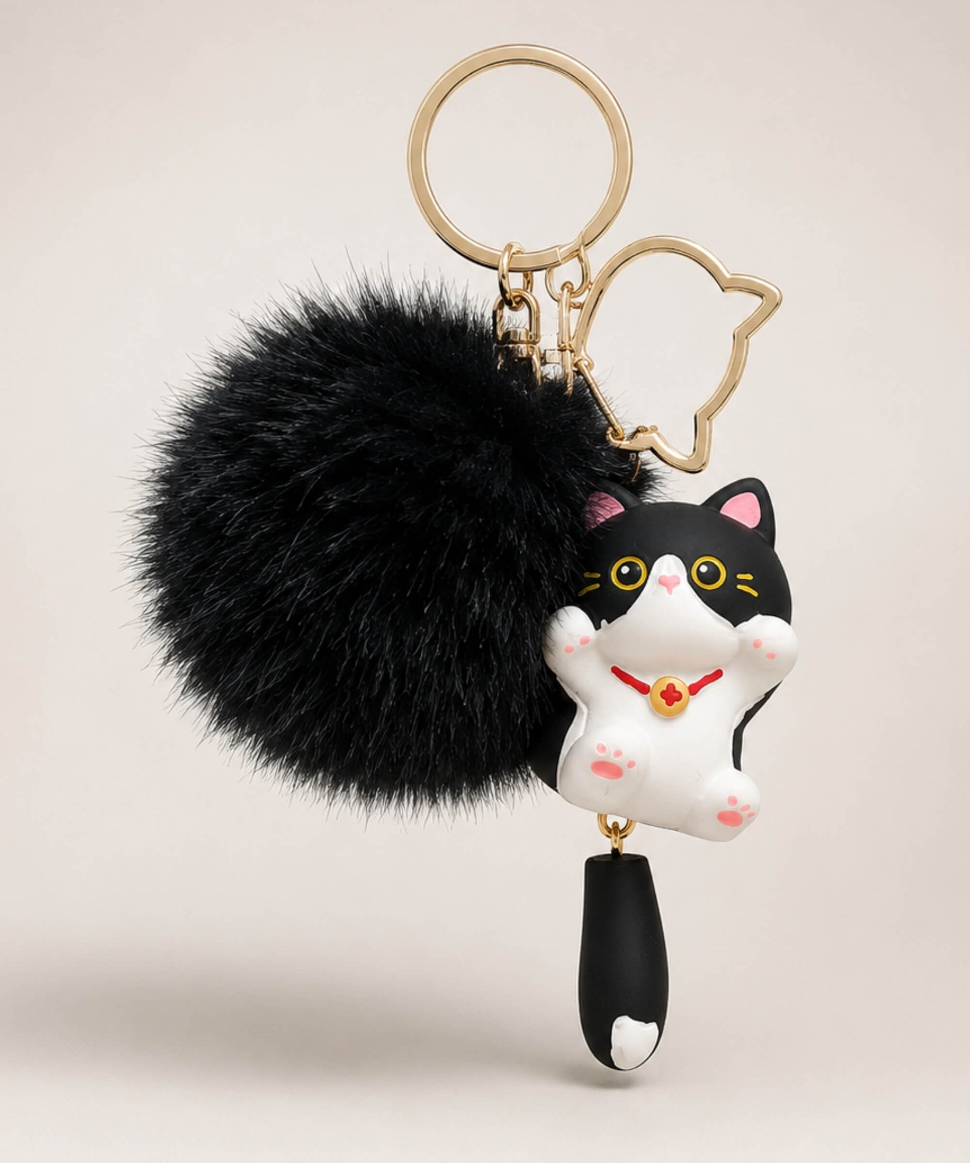 Black cat pom pom resin keychain with fluffy plush ball and gold hardware on a neutral background