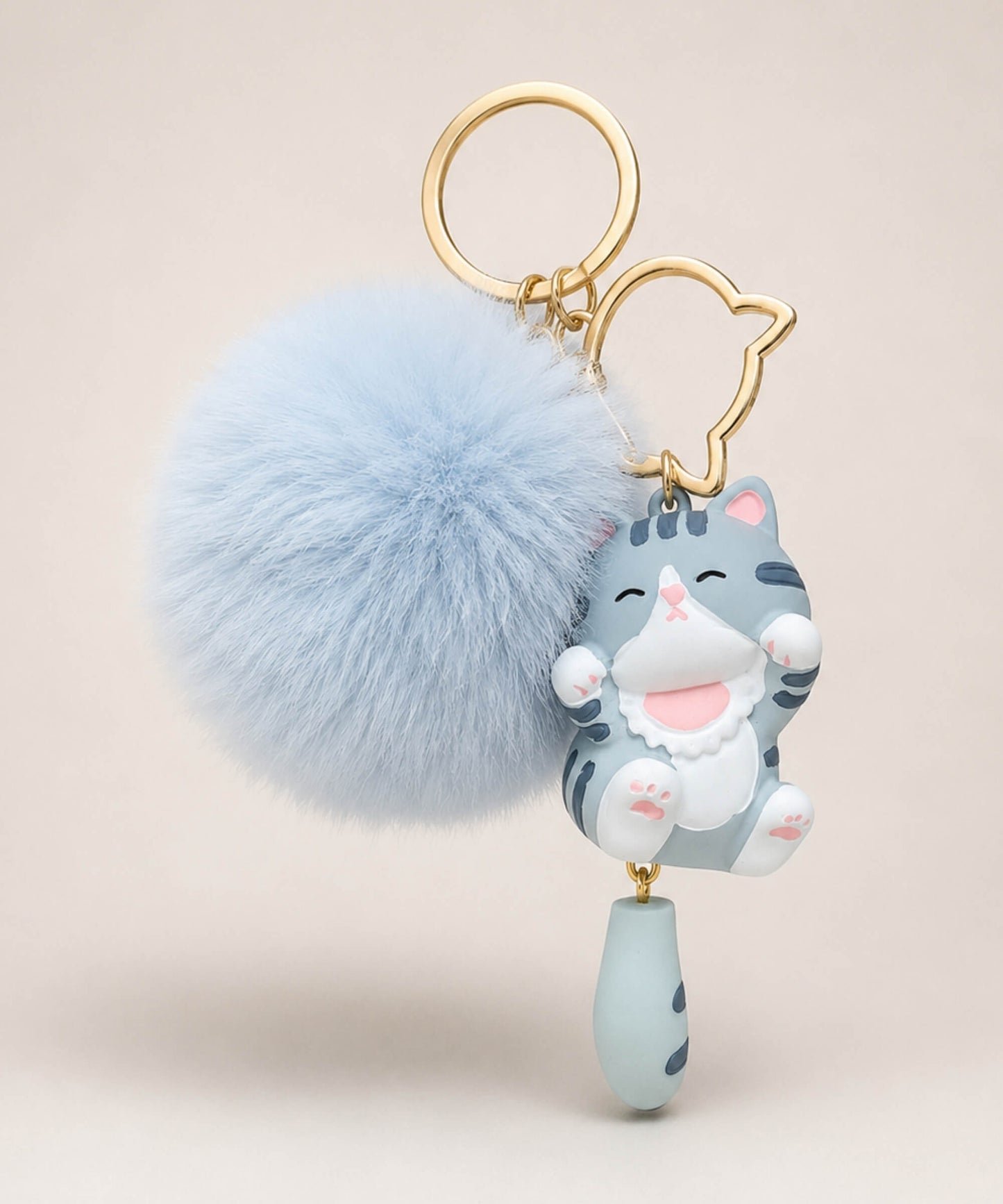 Blue cat pom pom resin keychain with fluffy plush ball and gold hardware on a neutral background