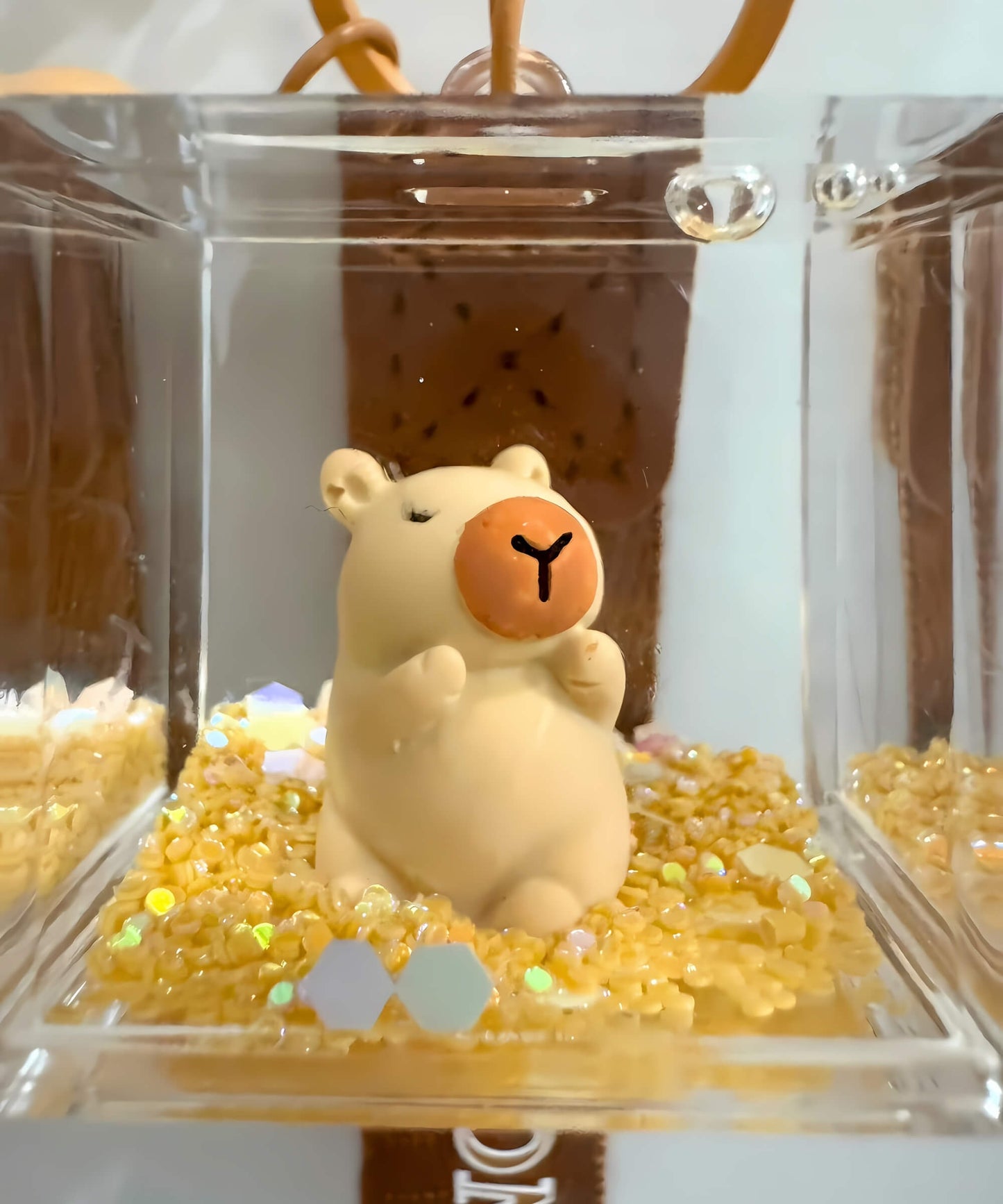 Close up of capybara liquid shaker keychain with floating glitter details