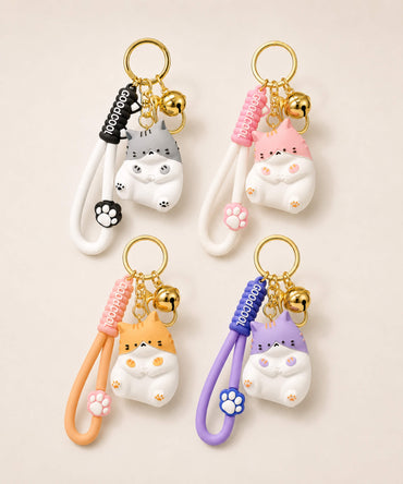 Four chubby cat resin keychains in grey, pink, orange and purple displayed together on a neutral background.
