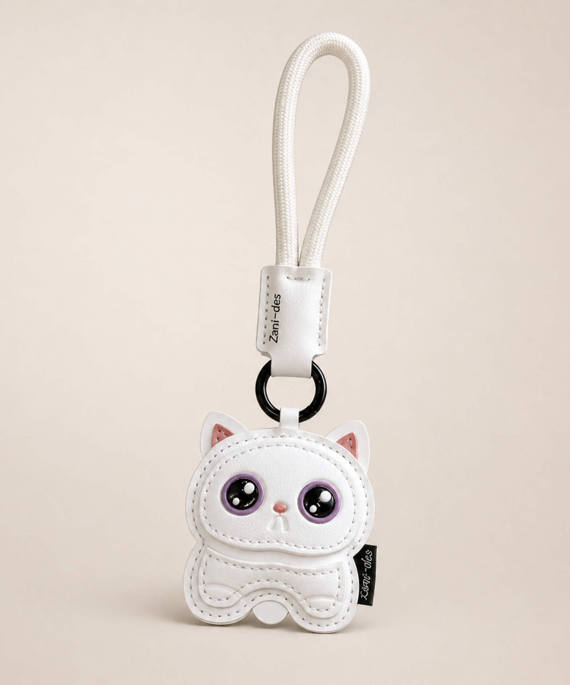 Cute Kitty PU leather keychain in white with purple eyes and wrist strap on a neutral studio background.
