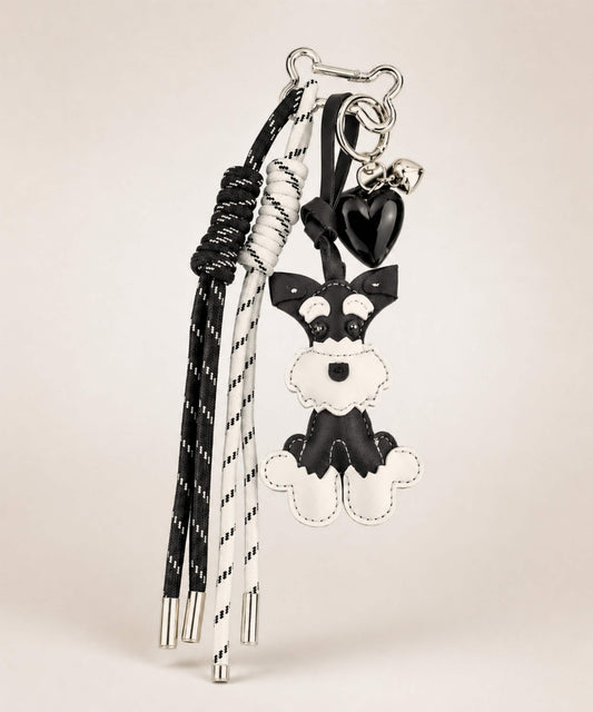 Black Cute Schnauzer faux leather bag charm with heart pendant and tassel cords on a minimal neutral background.