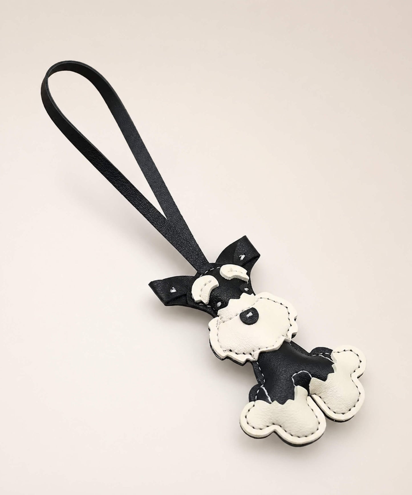 Black Cute Schnauzer faux leather keychain with wrist strap on a minimal neutral background.