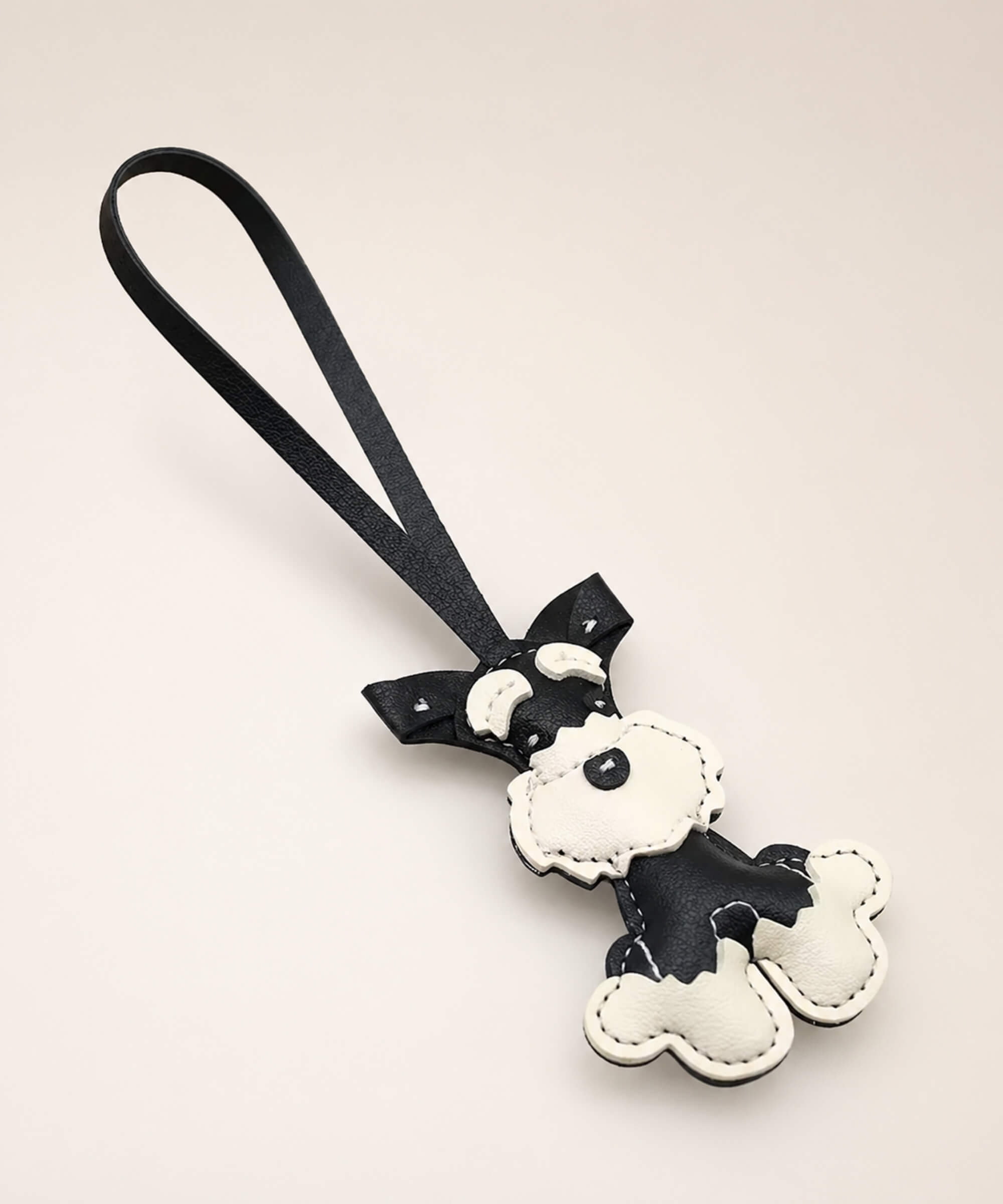 Black Cute Schnauzer faux leather keychain with wrist strap on a minimal neutral background.