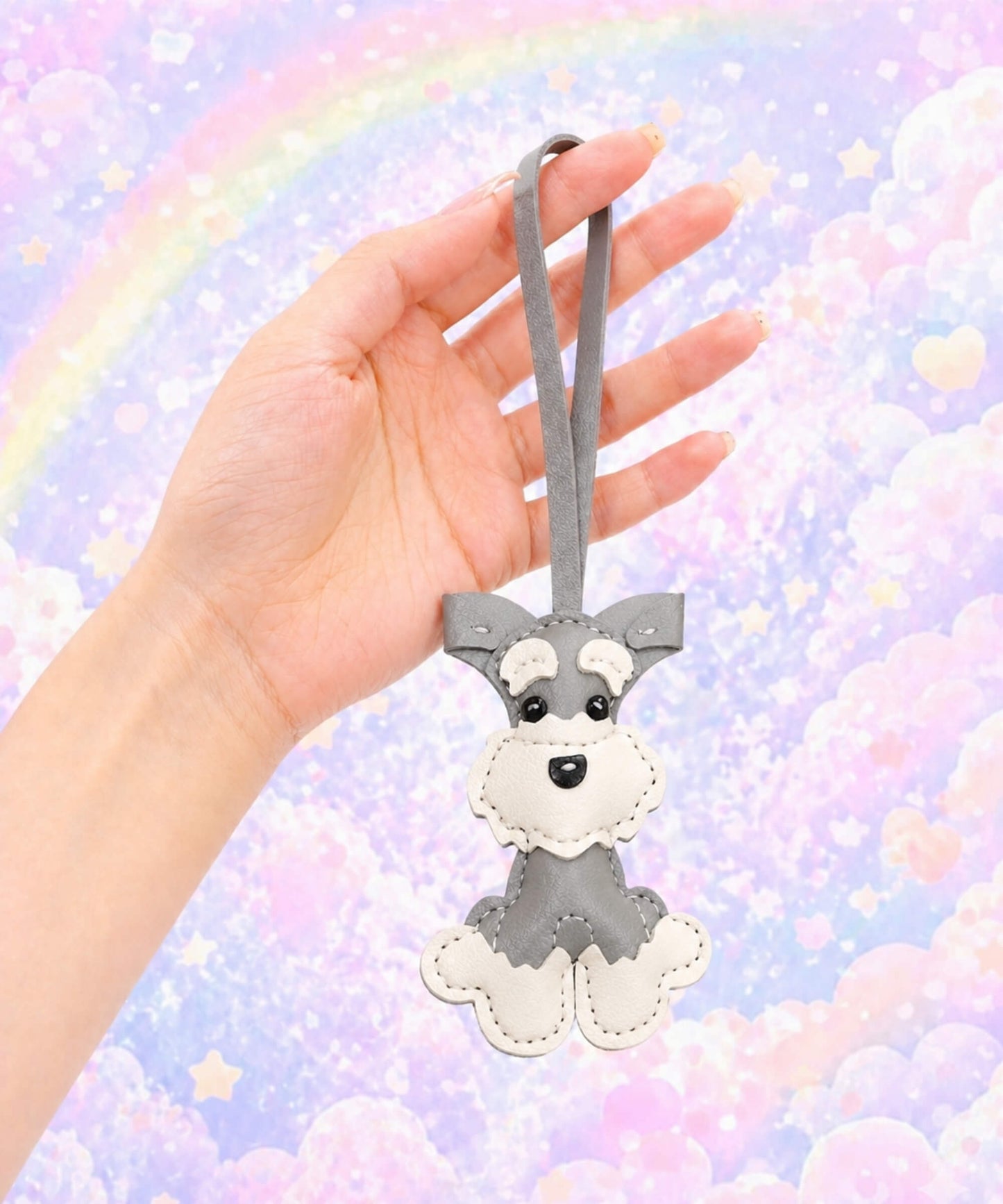 Grey Cute Schnauzer PU leather keychain held against a pastel rainbow cloud background.