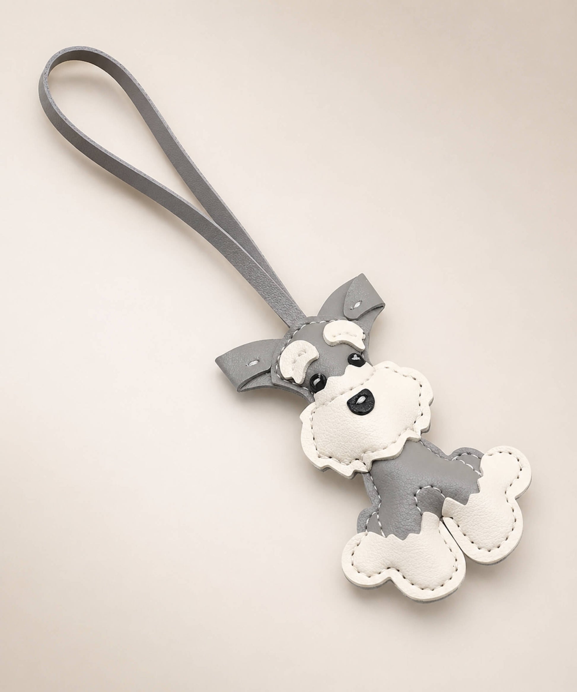 Grey Cute Schnauzer faux leather keychain with white details and wrist strap on a neutral studio background.