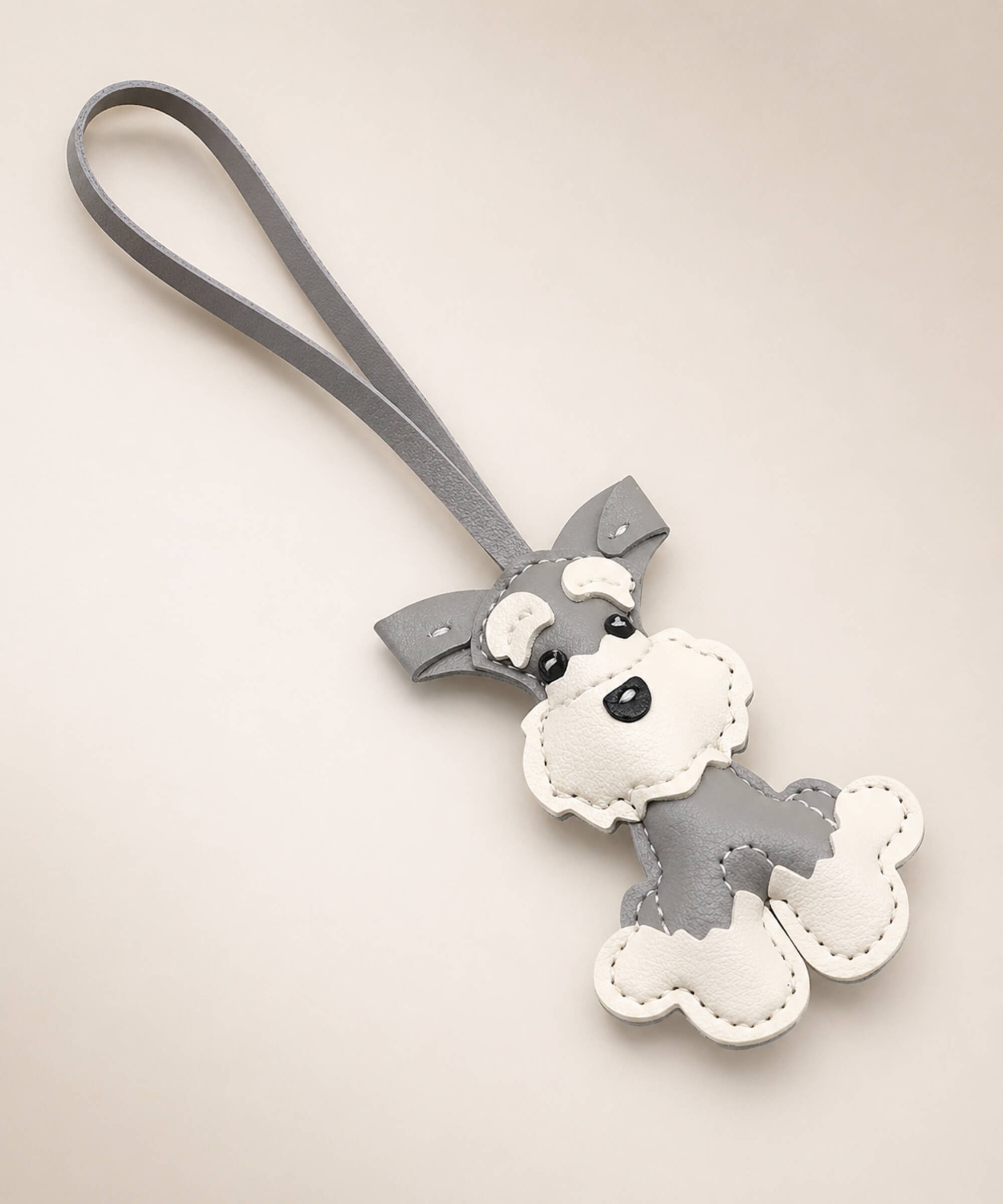 Grey Cute Schnauzer faux leather keychain with white details and wrist strap on a neutral studio background.