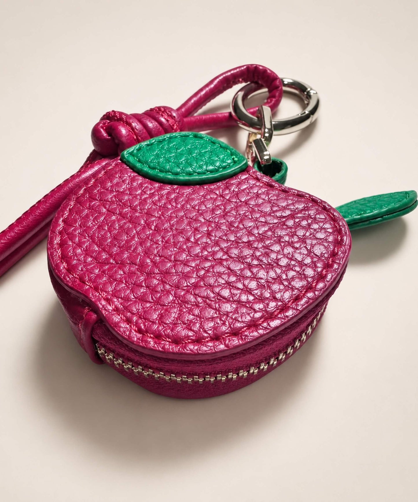 Close-up of apple fruit coin purse keychain with textured PU leather-style pouch, zipper detail and leaf charm