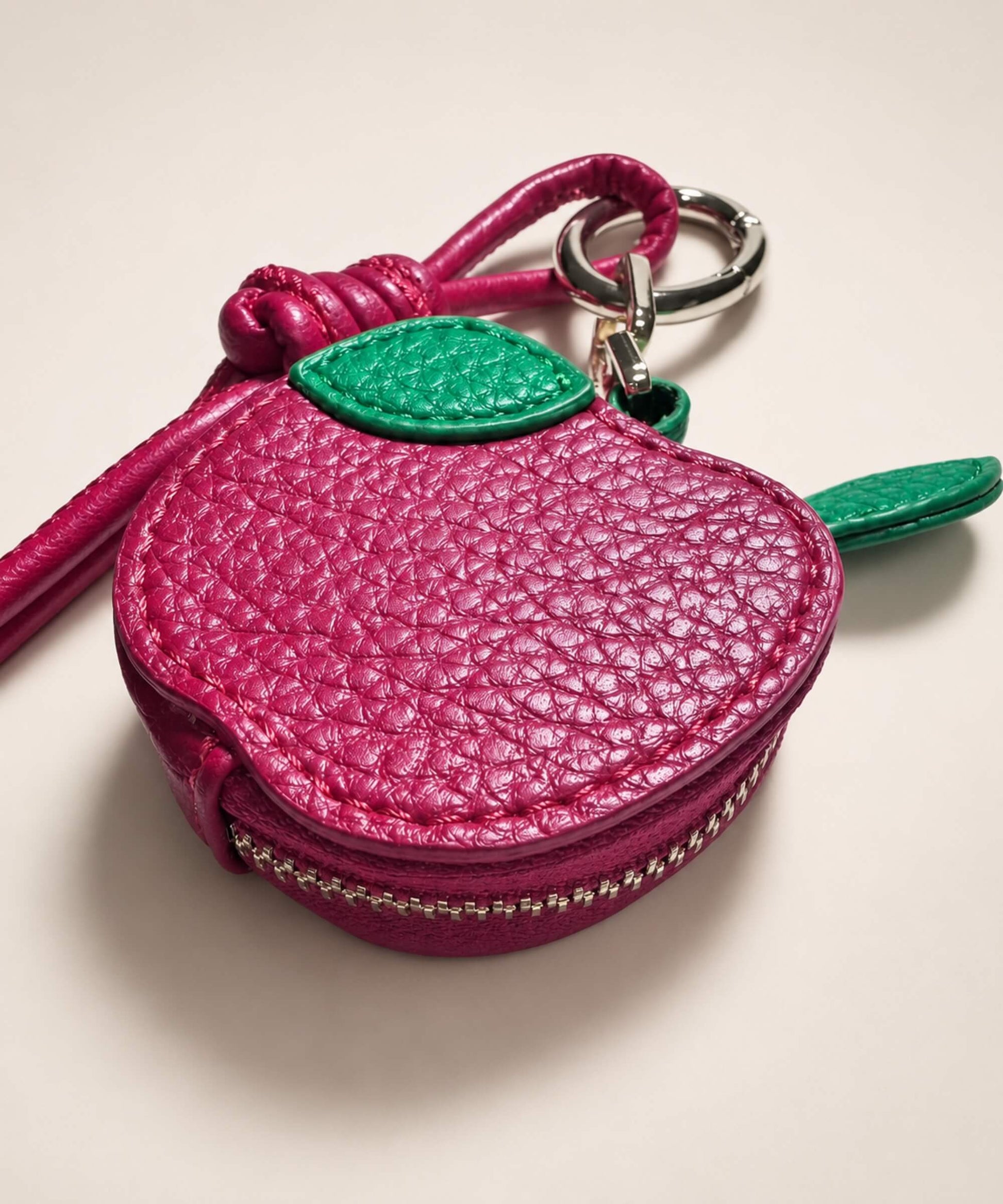Close-up of apple fruit coin purse keychain with textured PU leather-style pouch, zipper detail and leaf charm