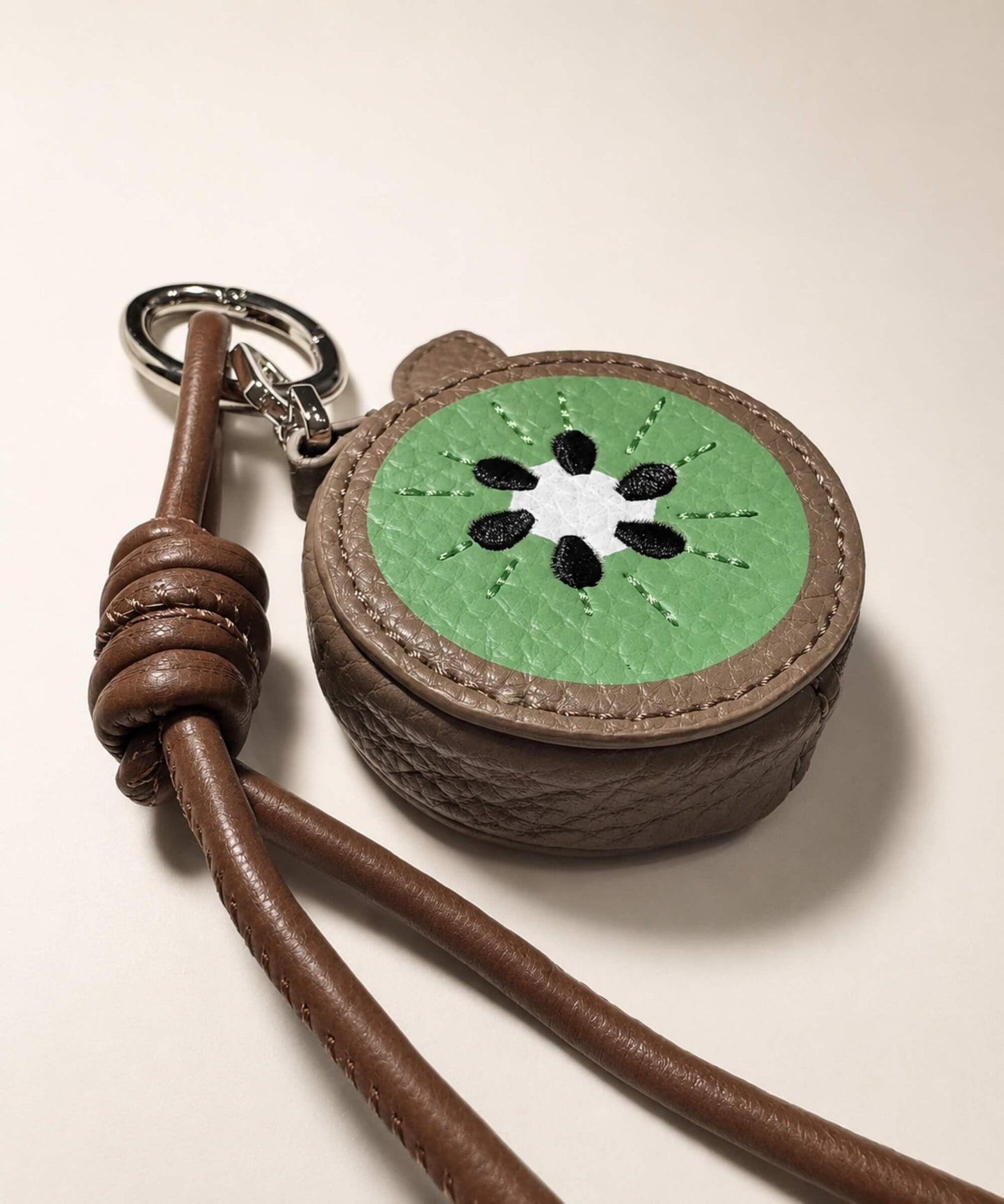 Close-up of kiwi fruit coin purse keychain with textured PU leather-style pouch and embroidered seed details