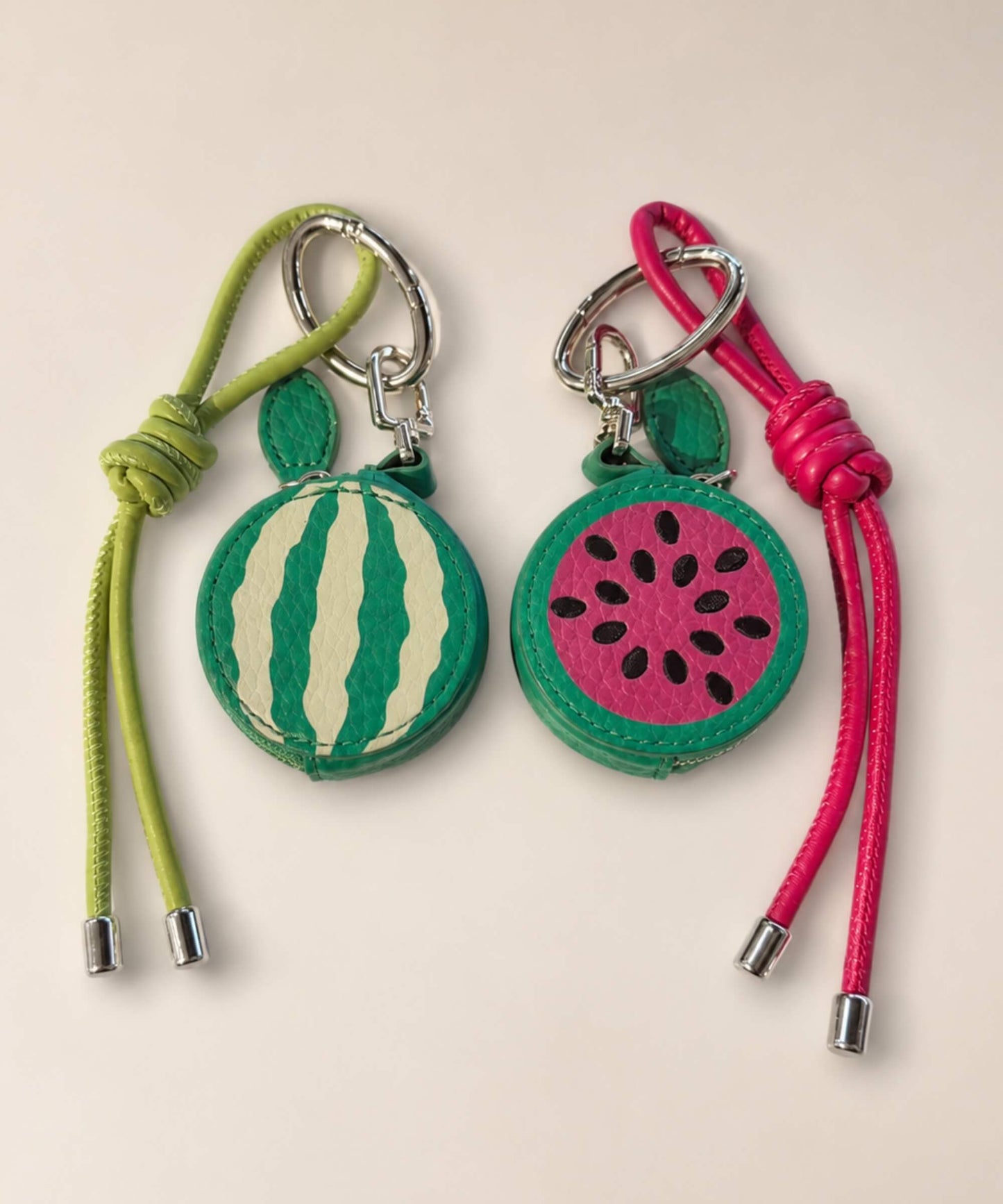 Two watermelon fruit coin purse keychains with green and pink straps, sliced watermelon pouch designs and PU leather-style texture