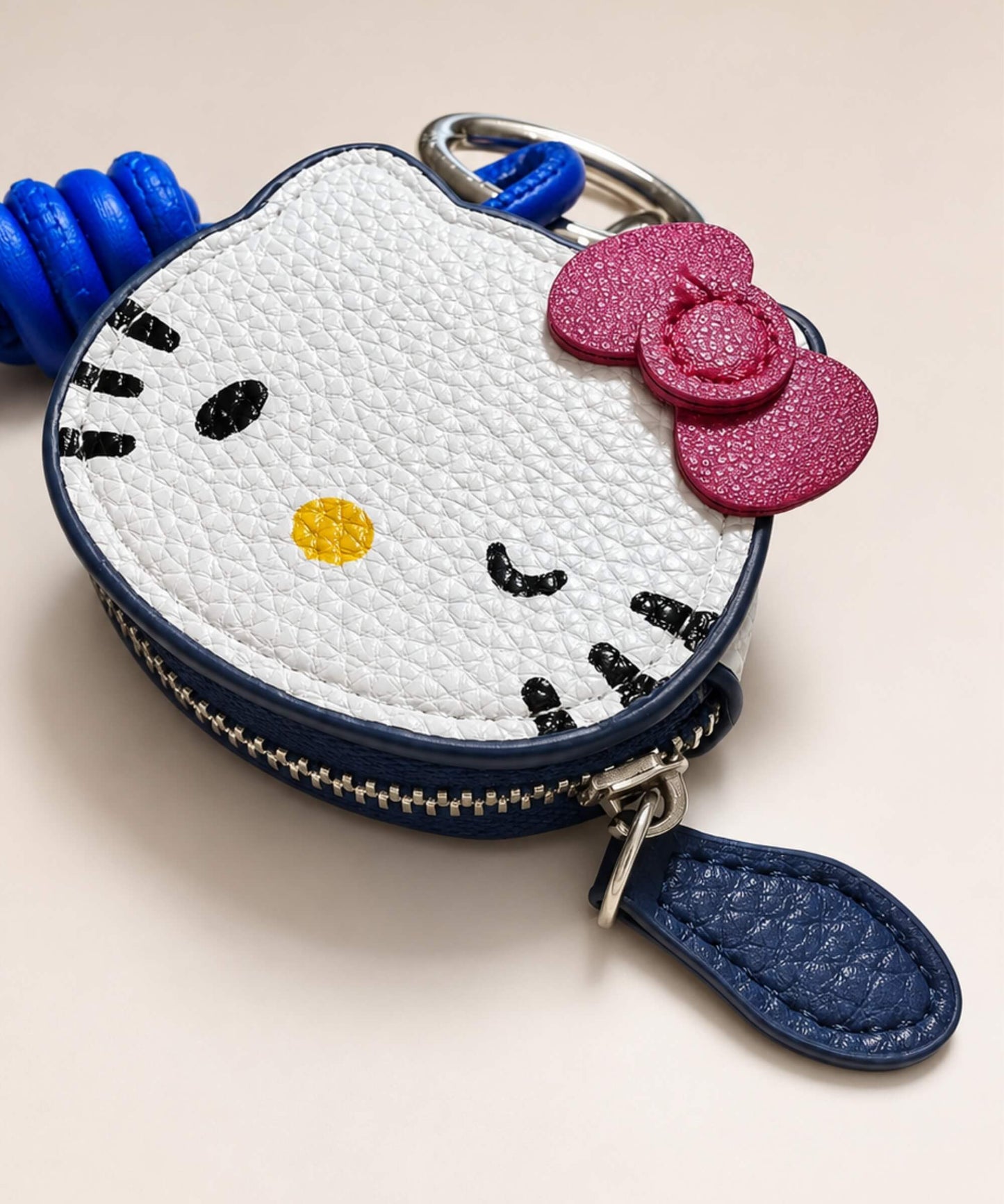 Close-up of Hello Kitty coin purse keychain with textured PU leather-style pouch, bow detail and zipper