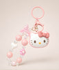 Hello Kitty pink beaded keychain with bow, heart and flower charm details on a neutral background