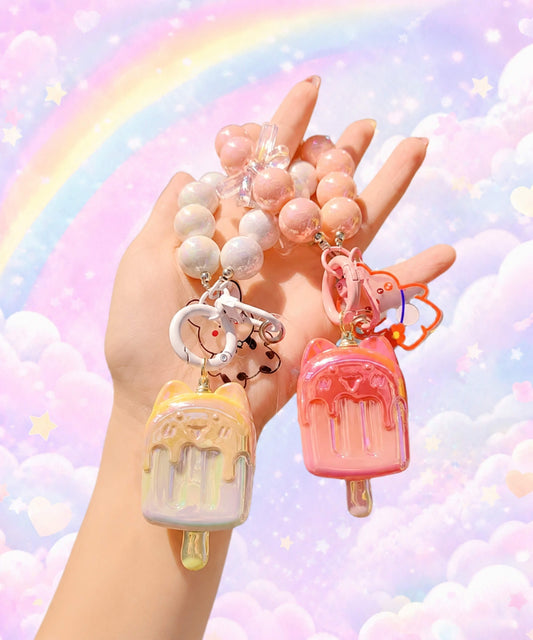 Ice cream beaded keychains in assorted colours held in hand with a pastel rainbow background