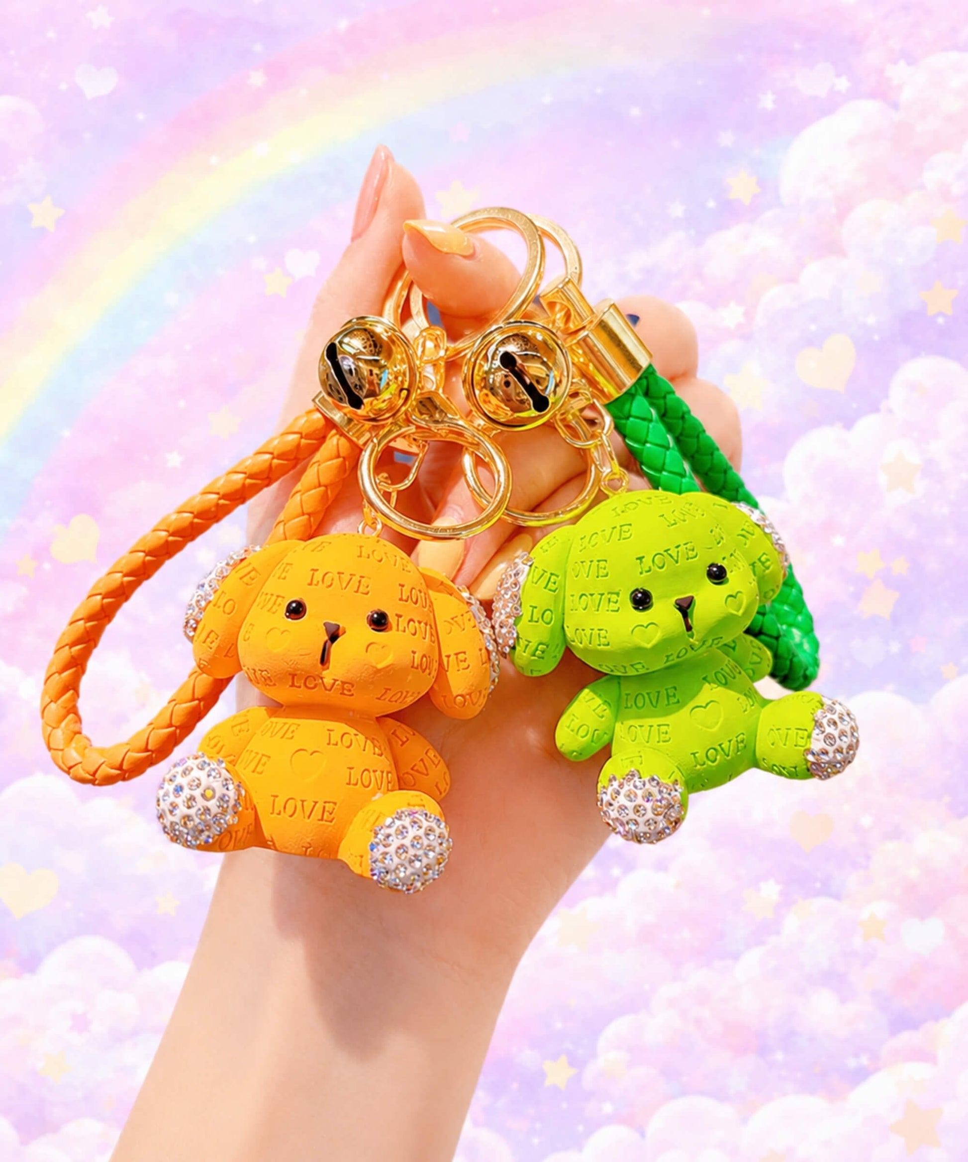 Hand holding orange and green love puppy resin keychains against a pastel rainbow background.