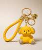 Yellow love puppy resin keychain on a neutral background.