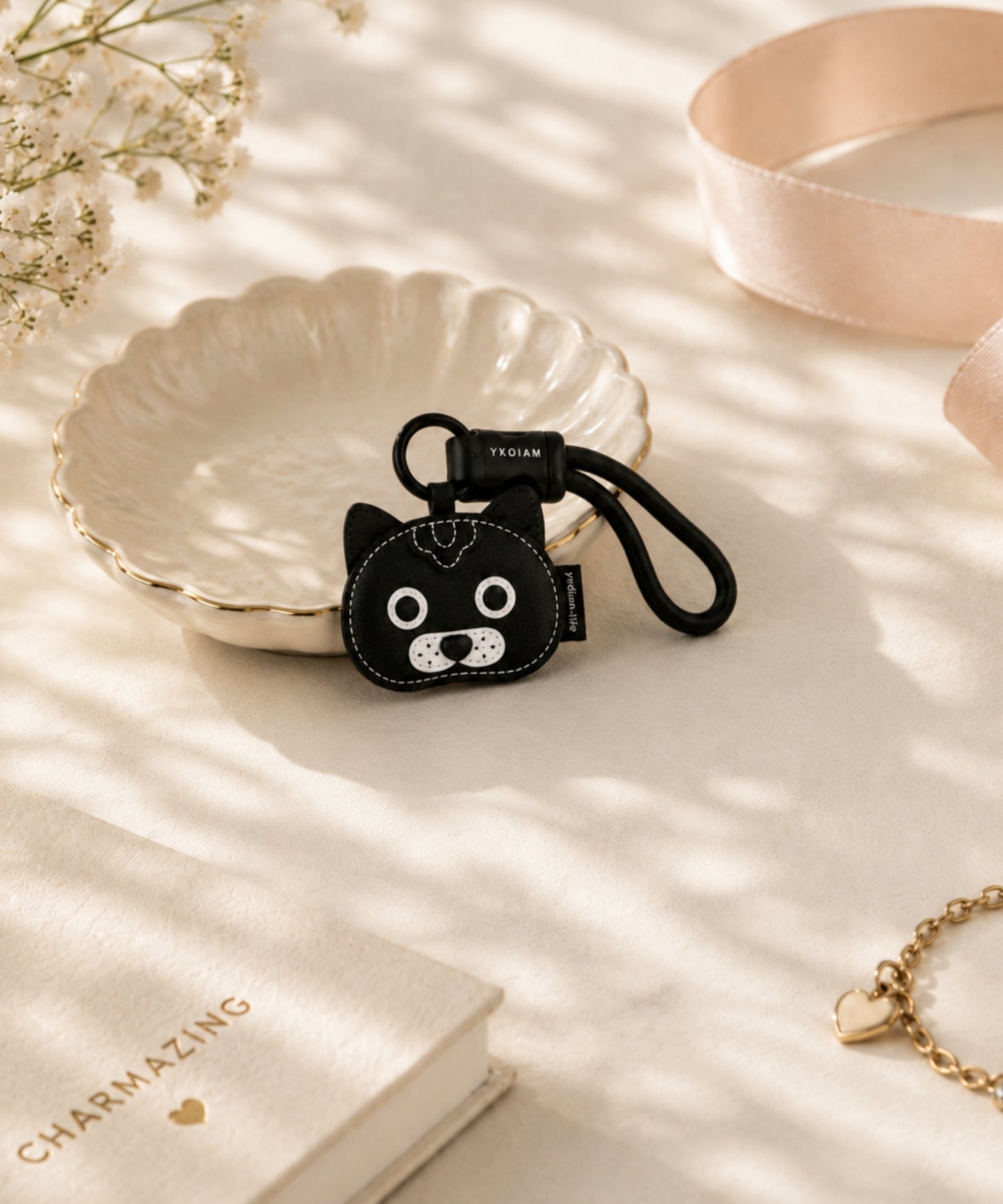 Black cat pet face PU leather bag charm keychain styled in a soft lifestyle scene with decorative props.