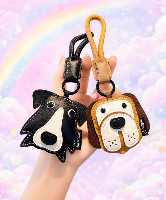 Hand holding border collie and beagle pet face PU leather bag charm keychains against a pastel rainbow background.