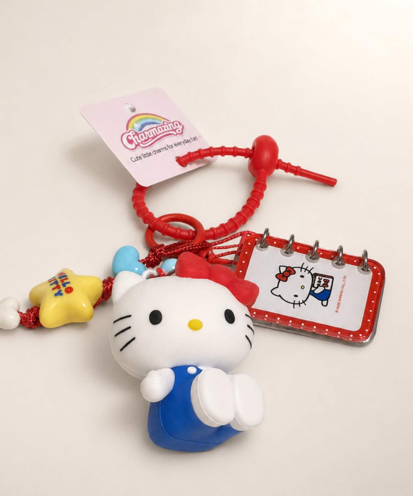 Close-up of Hello Kitty book Sanrio keychain with red strap, character charm and mini notebook detail