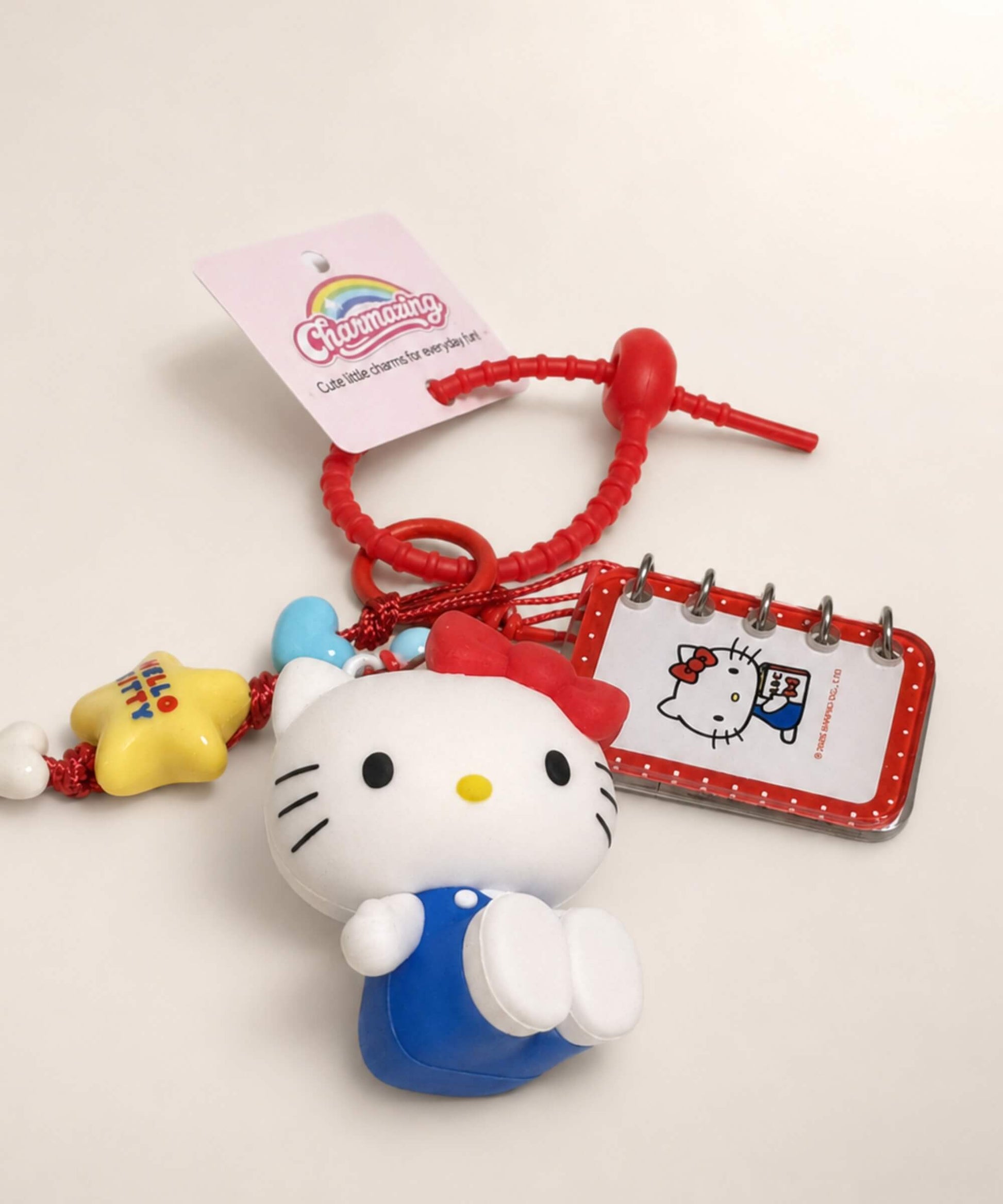 Close-up of Hello Kitty book Sanrio keychain with red strap, character charm and mini notebook detail