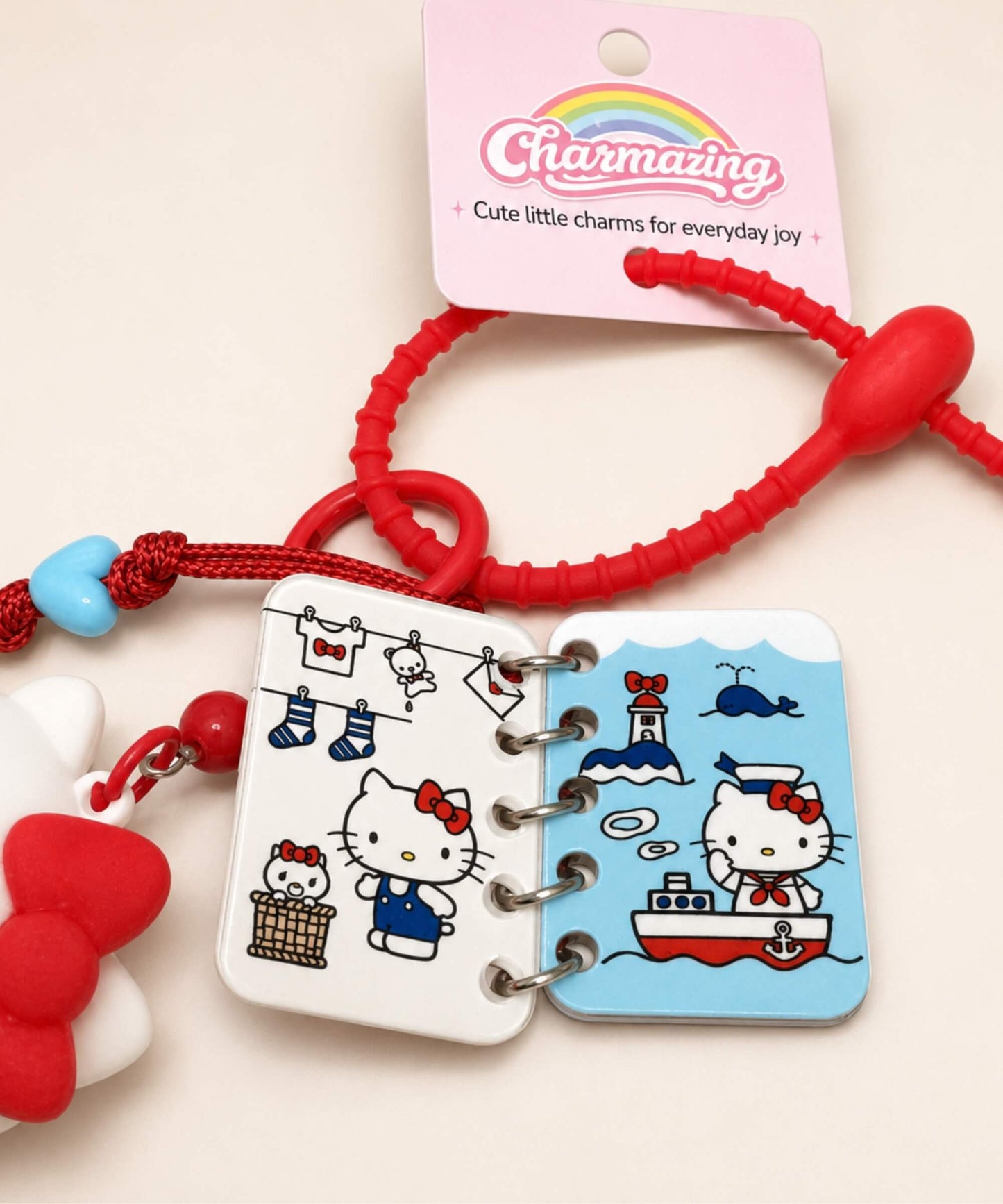 Close-up detail of Hello Kitty book charm showing mini illustrated pages and red strap