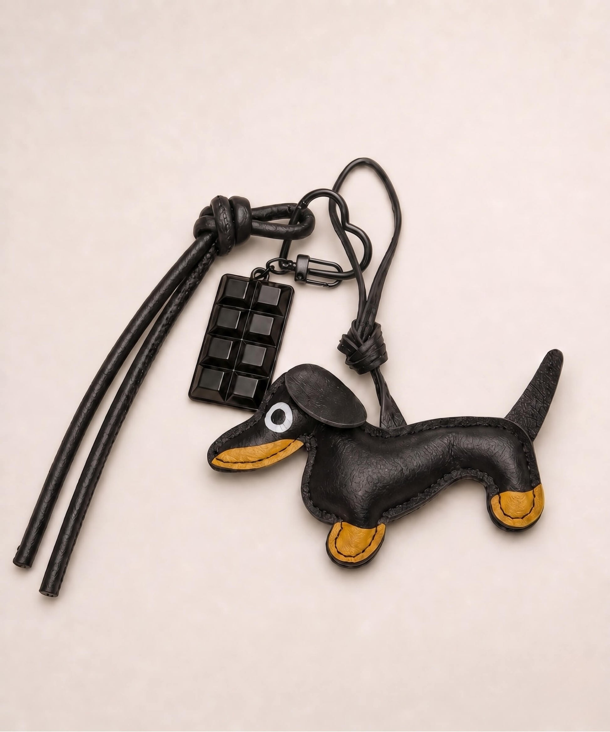Black sausage dog PU leather bag charm keychain with a black chocolate charm styled on a neutral background.