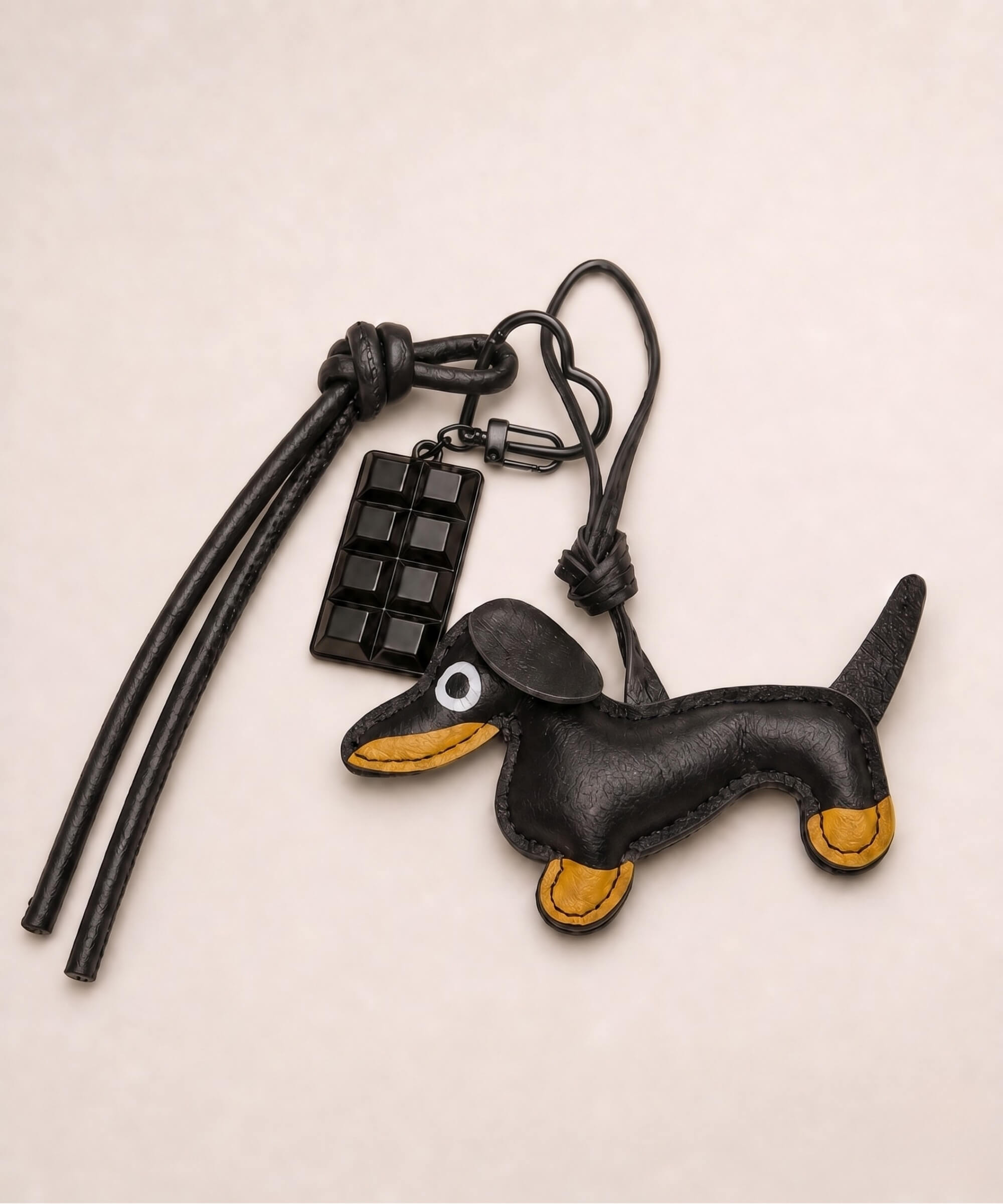 Black sausage dog PU leather bag charm keychain with a black chocolate charm styled on a neutral background.