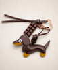 Brown sausage dog PU leather bag charm keychain with a chocolate charm styled on a neutral background.