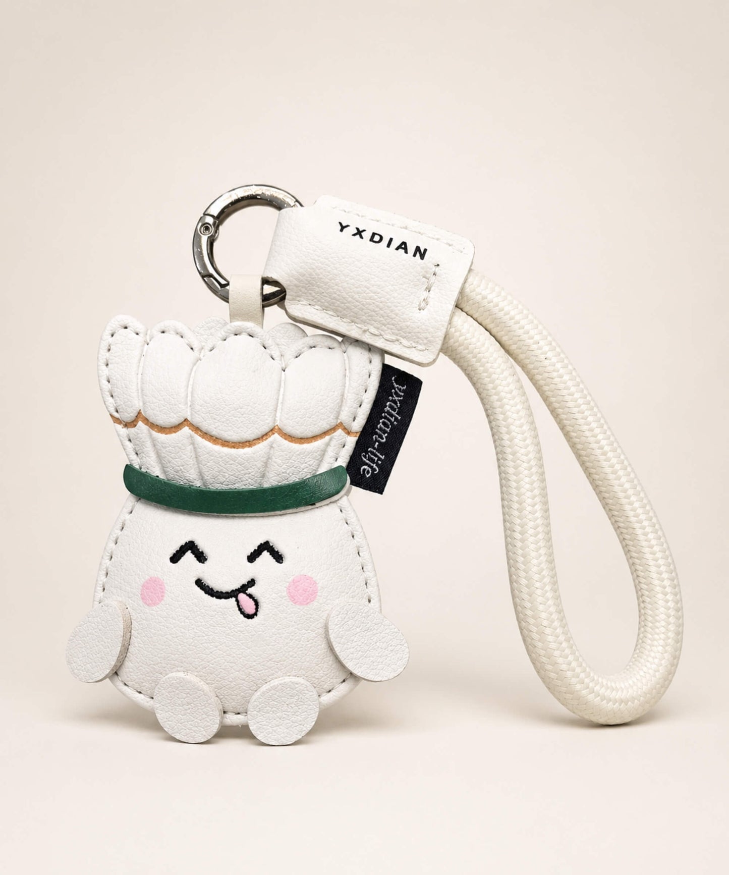 White badminton PU leather bag charm keychain with cream wrist strap on a neutral studio background.