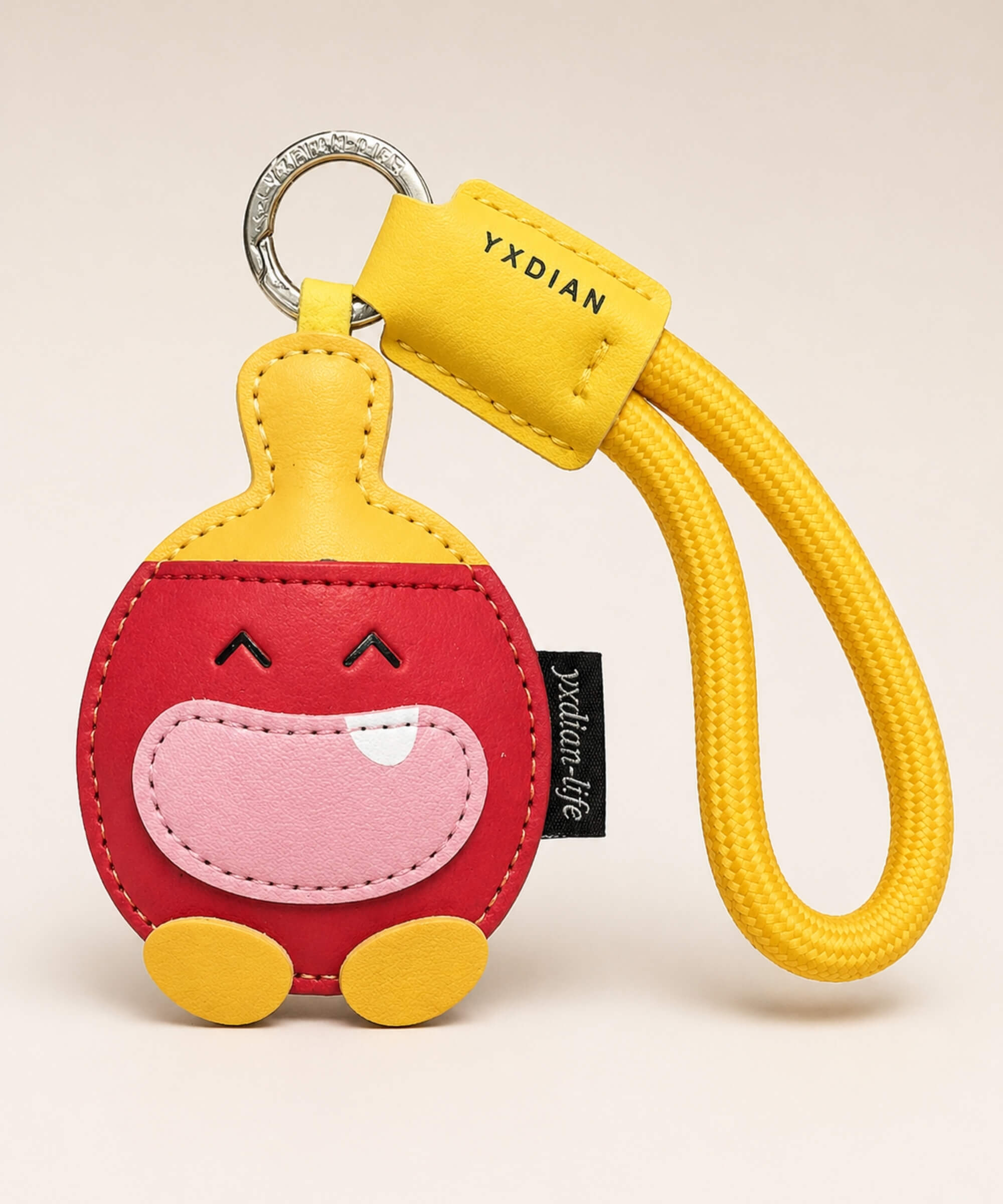Red table tennis PU leather bag charm keychain with yellow wrist strap on a neutral studio background.